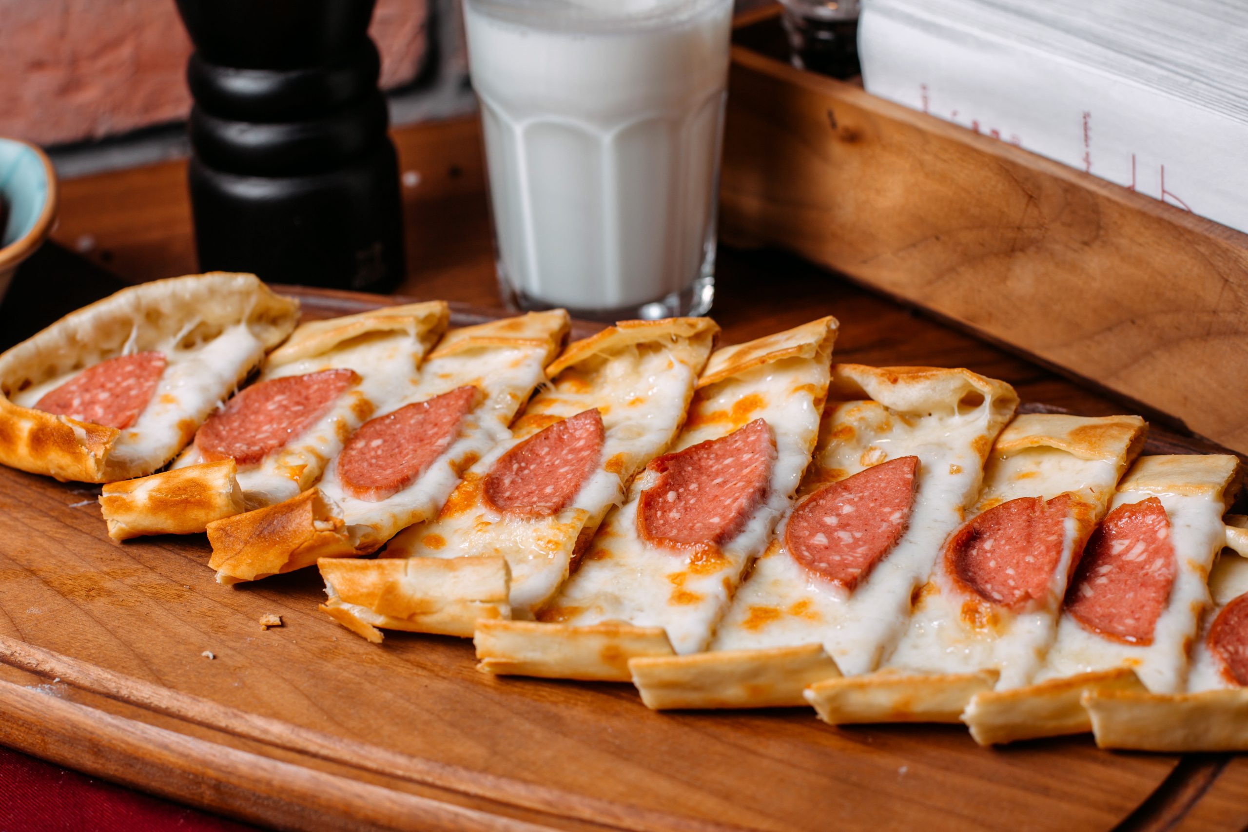 side view of turkish pide with salami sausage arranged on a wooden cutting board